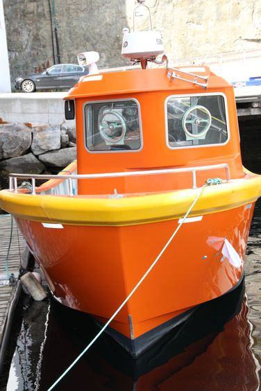 Orange båt ligger fortøyd ved kai