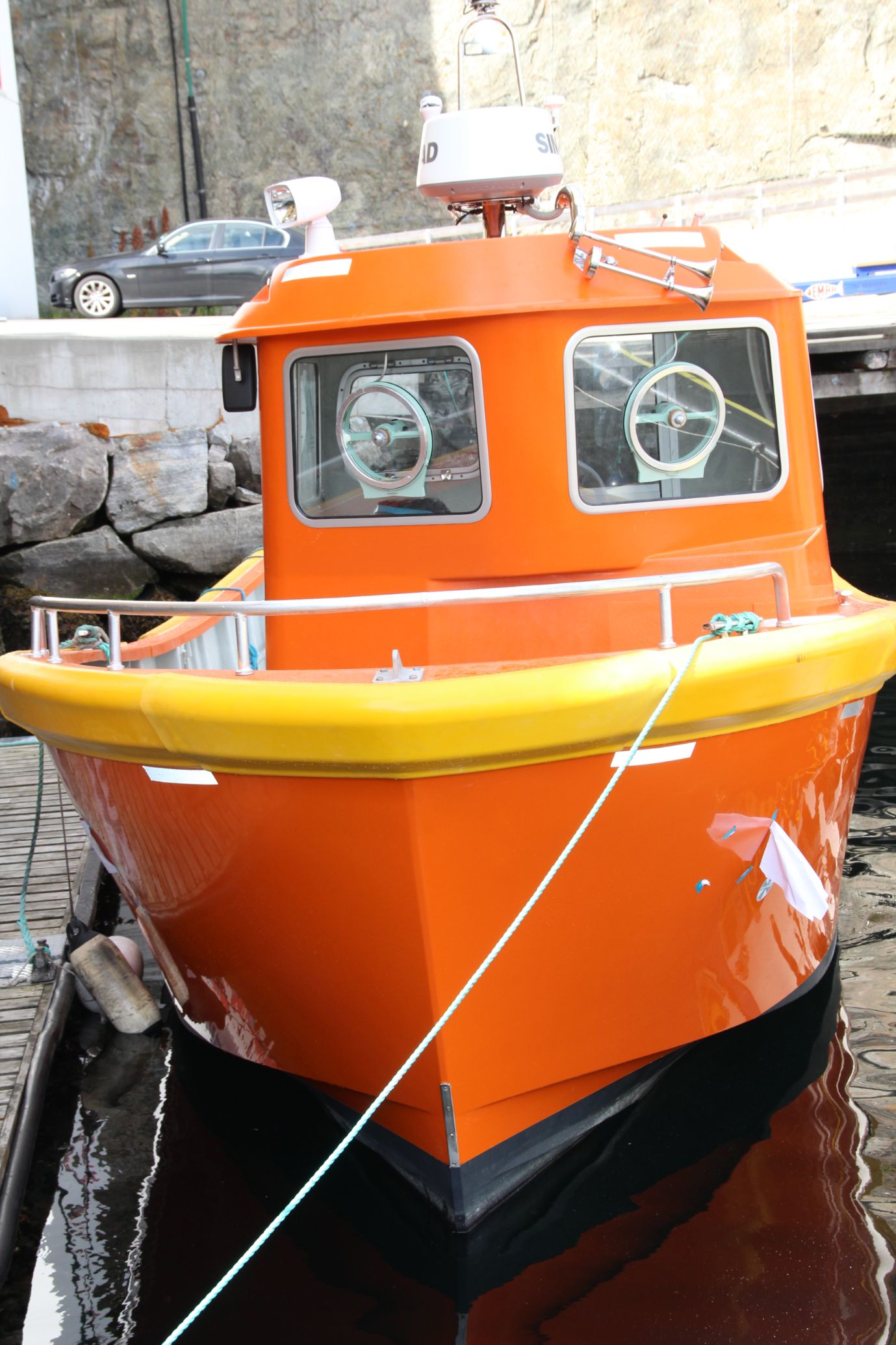 Orange båt ligger fortøyd ved kai